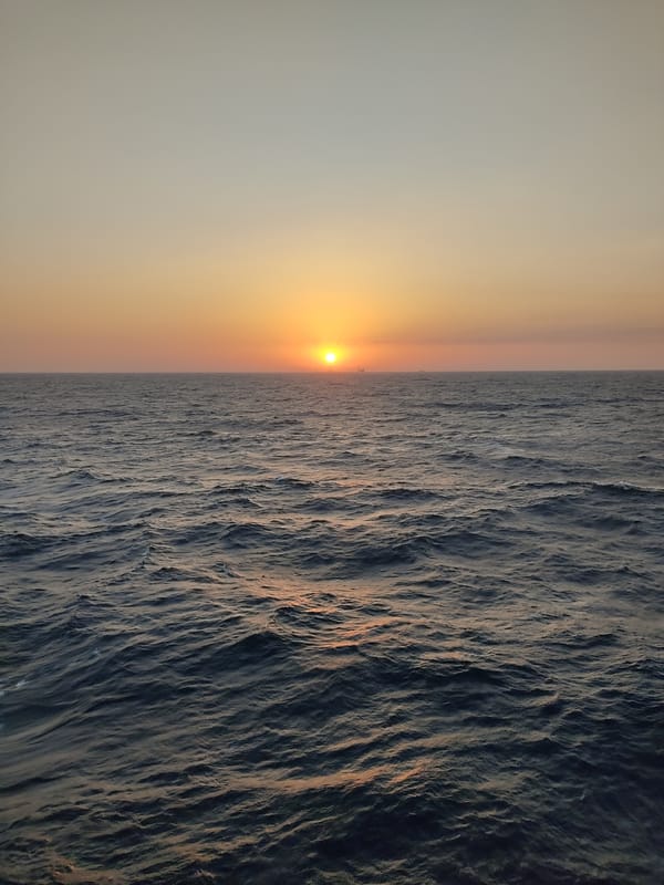 Open ocean through the day, sunset to floodlit sea