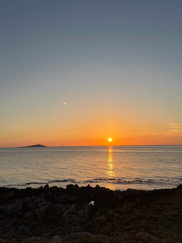 Golden hour over the Palermo coastline, sailboat on the horizon