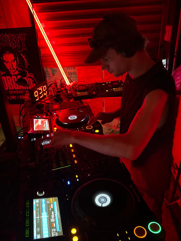 DJ set underway at a Bangkok club, red lights and full booth