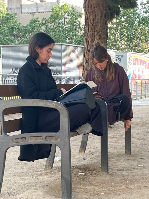 Two women sit on park benches in Barcelona