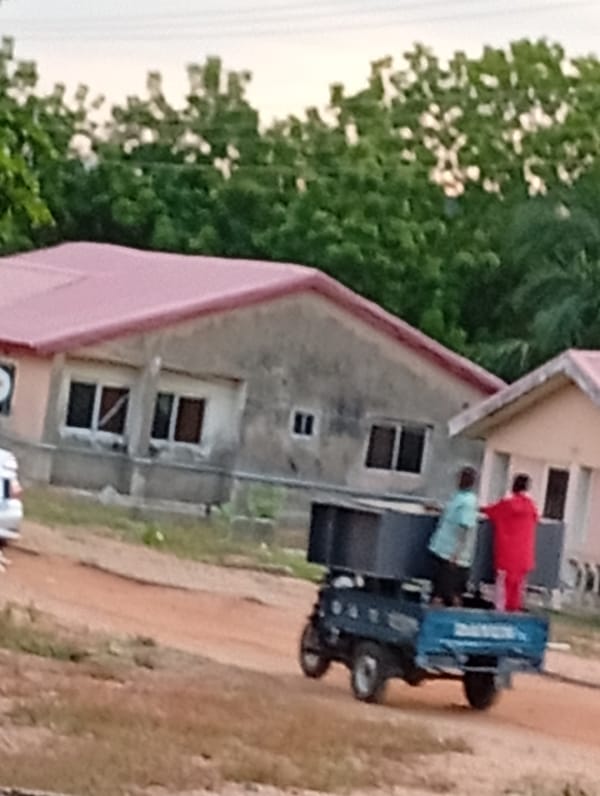 Two riders spotted on blue three-wheeler near rural building