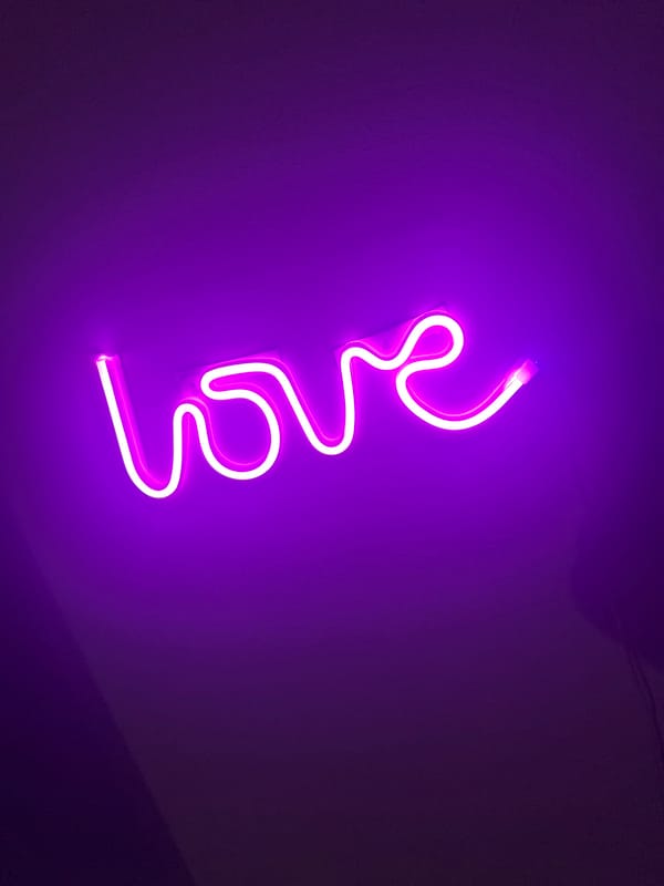 Neon love sign glows on purple wall in Kudrovo