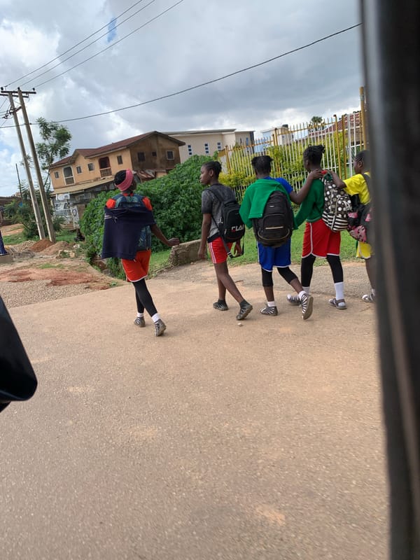 Students moving through Jos streets on a cloudy afternoon