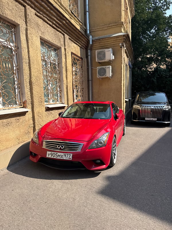 Red coupe and white Miata parked near ornate Moscow building