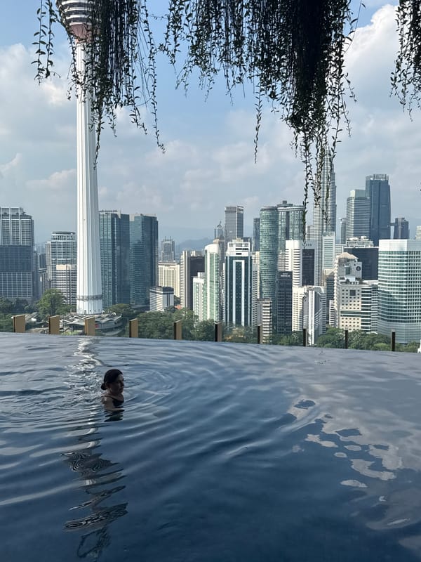 Woman enjoys rooftop infinity pool overlooking Kuala Lumpur skyline