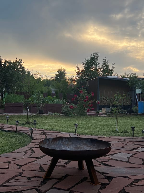 Dusk settles over a rustic backyard with a fire pit in Luch