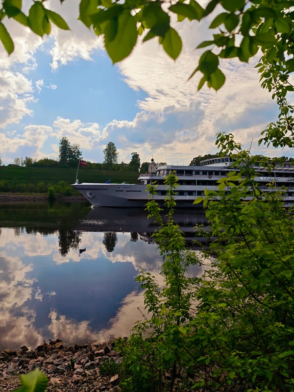 Cruise ship sails past neoclassical building in Russian town