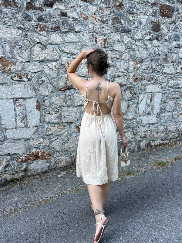 Woman in beige dress walks along stone-walled road in Podgorica