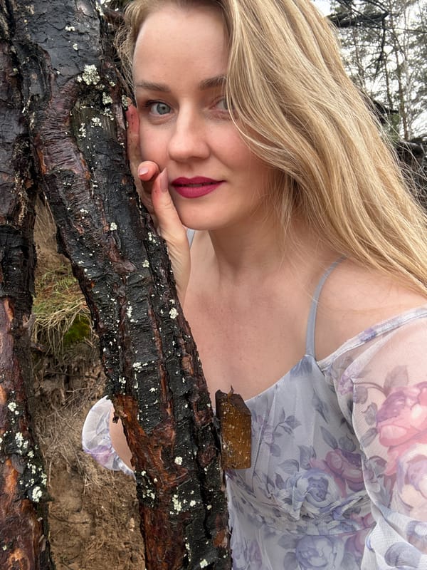 Woman poses for outdoor portraits among tree roots in Chaikovsky