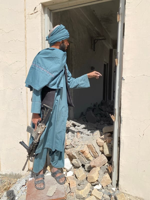 Armed men survey heavily damaged building in Mandisar, Afghanistan