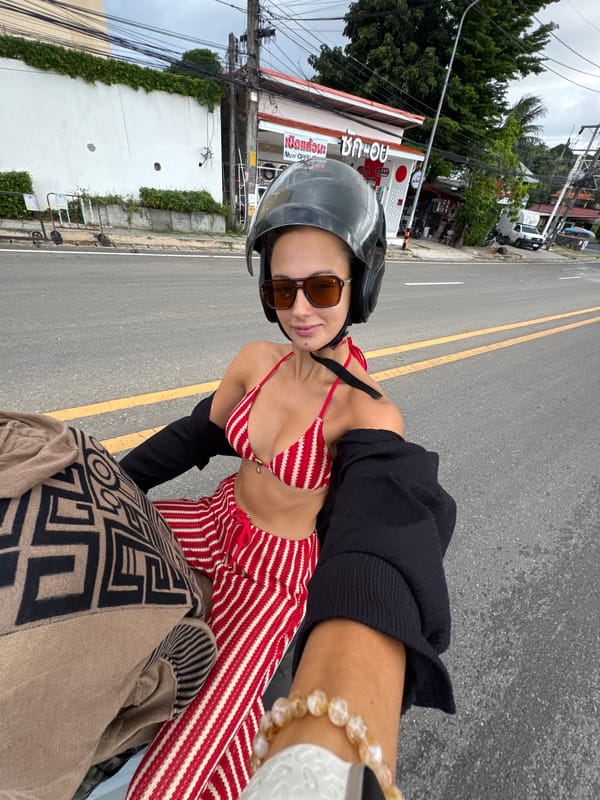 Woman in bikini top rides motorcycle on wet Rawai road