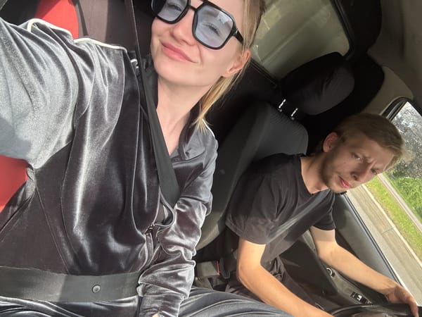 Two people observed seated in vehicle, one in tracksuit