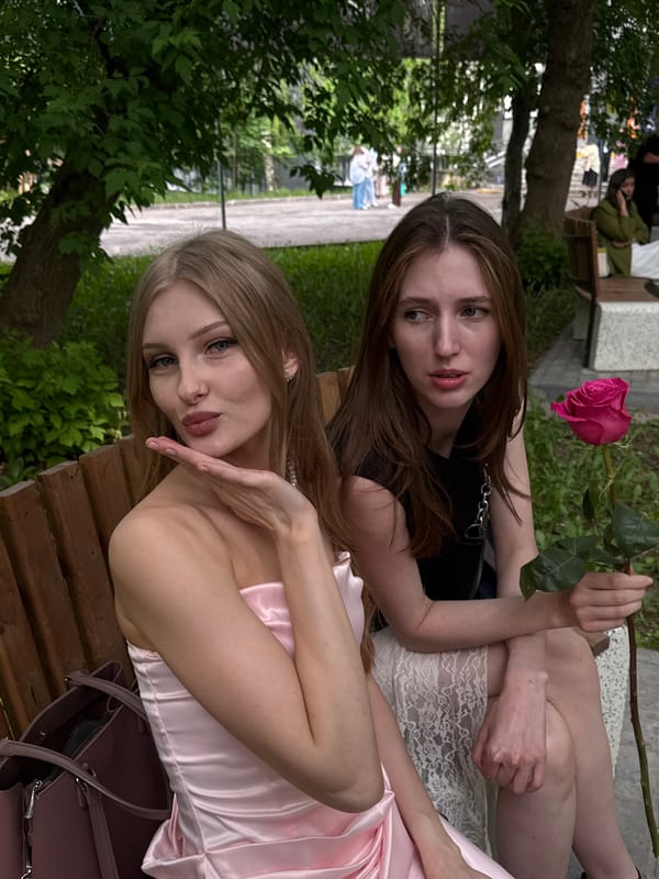 Two women share casual moment on park bench in Perm