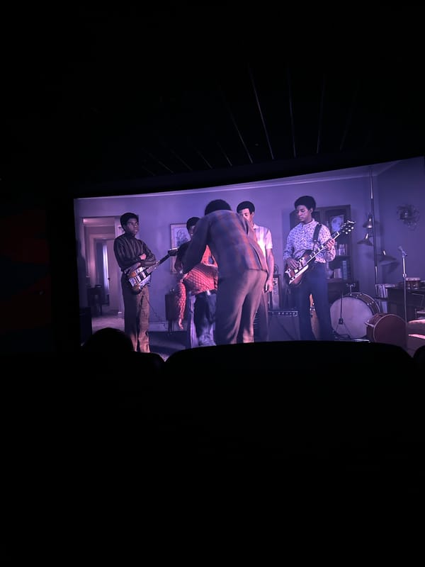 Screen displays musical performance to gathered viewers