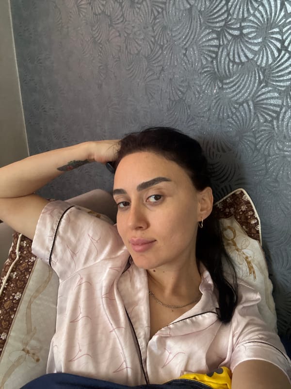 Woman photographed in pink pajamas on bed in Tbilisi