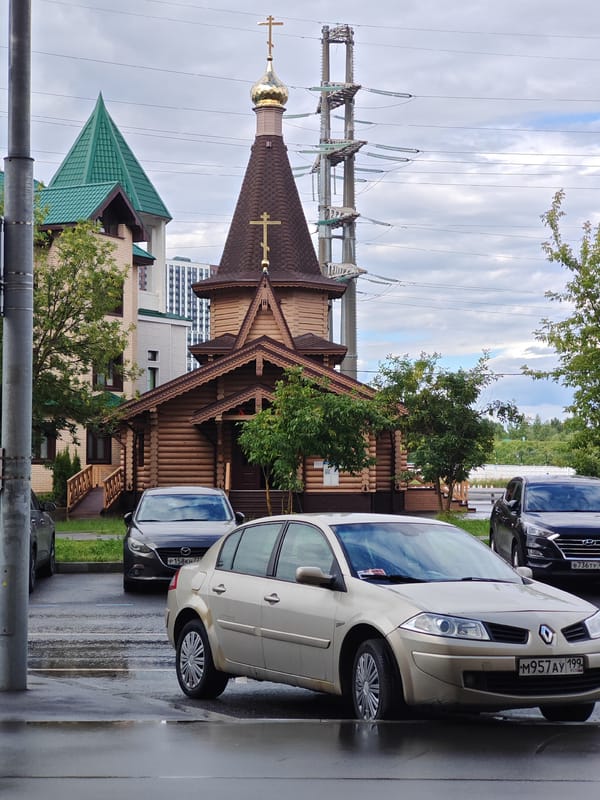 Wooden Orthodox church alongside modern brick building in Moscow