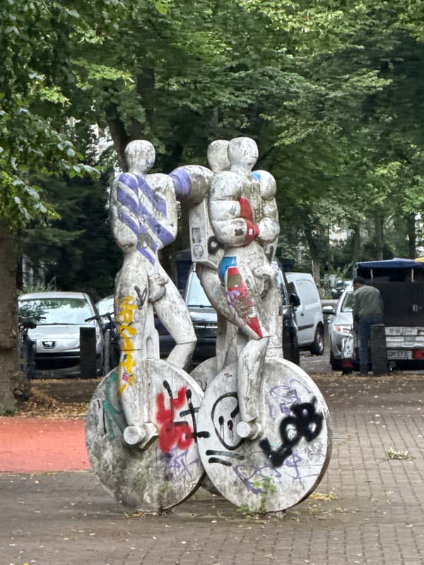 Street-level Hamburg: brickwork, café terrace, and graffiti sculpture