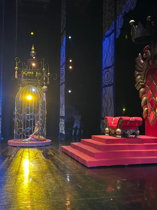Theatrical stage set with gilded birdcage and dramatic lighting