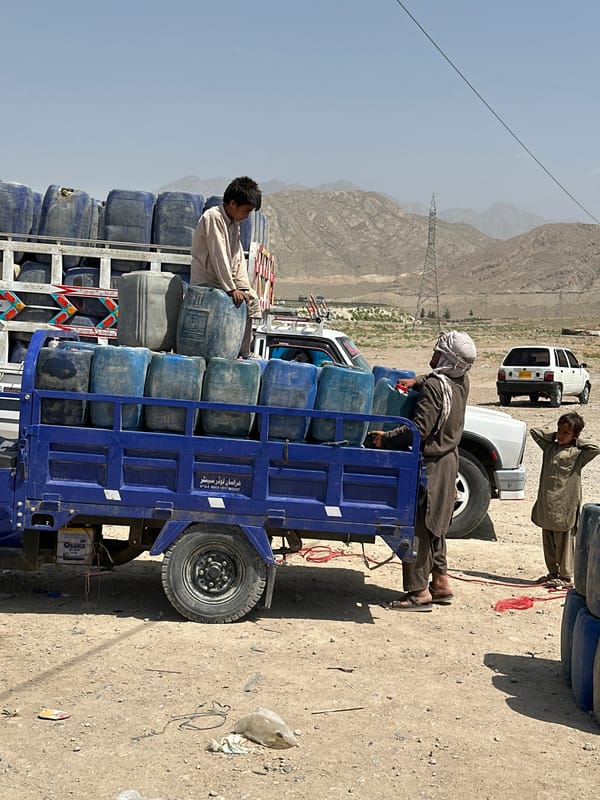 Blue truck convoy transports containers in Pakistan mountains