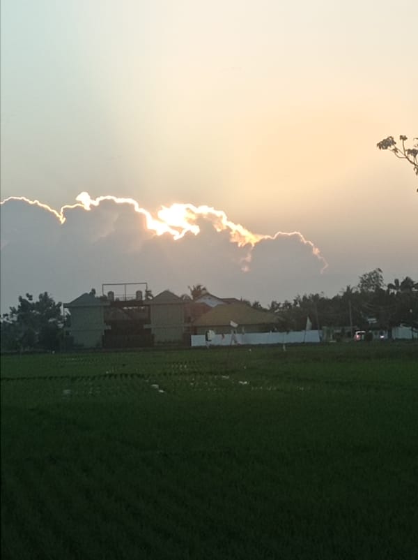 Golden sunset breaks through clouds over rural Kelurahan Oluhuta Utara