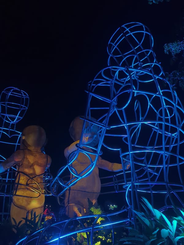 Illuminated wire-frame human sculptures displayed at night in Kediri
