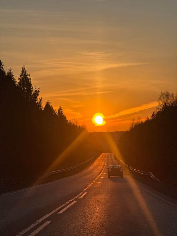 Car drives toward sunset on Chaikovsky road