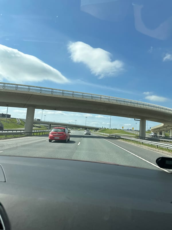 Highway drive through city outskirts past pylons and roadside landmarks