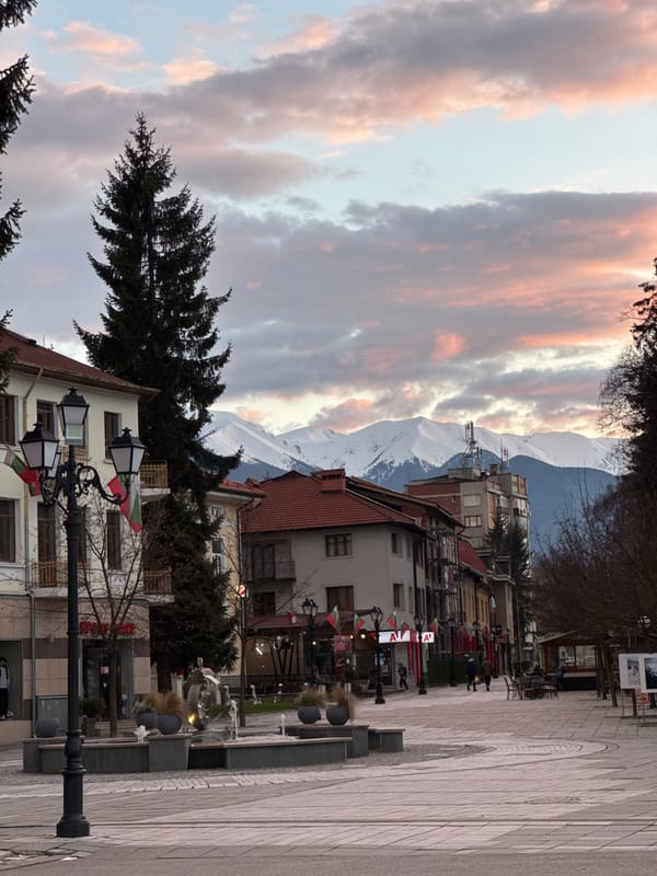 Pink-tinged clouds observed over mountain street scene in Razlog