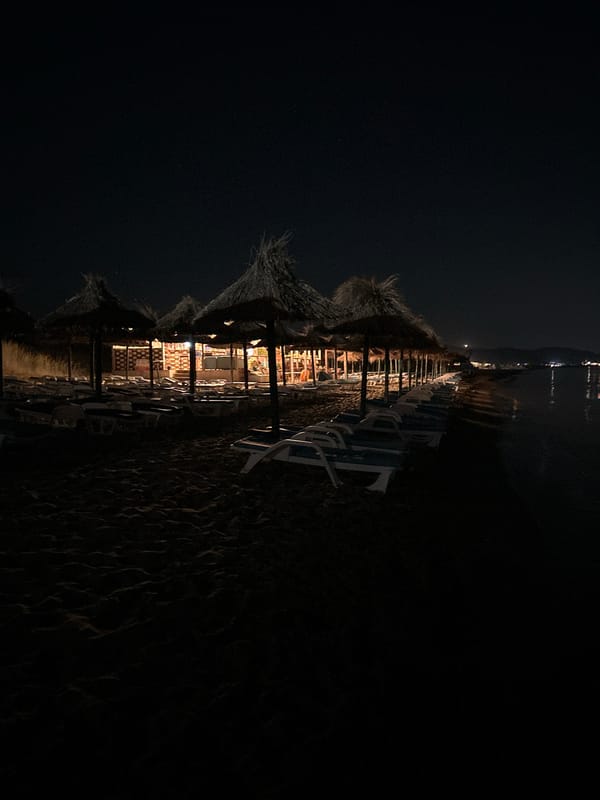 Empty beach and lit patio at a coastal venue after dark