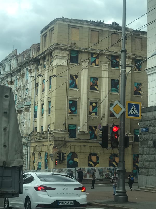 Art adorns damaged Kharkiv building as delivery cyclist navigates streets