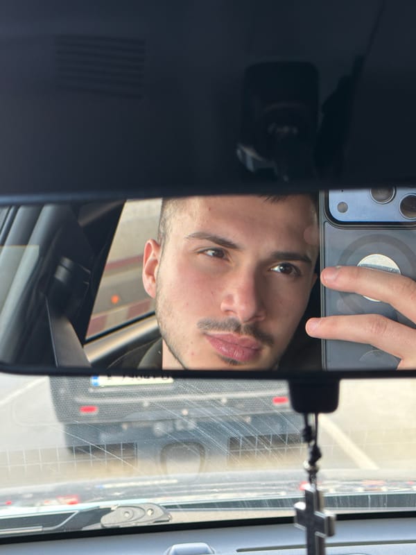 Man uses phone in car captured in rearview mirror reflection