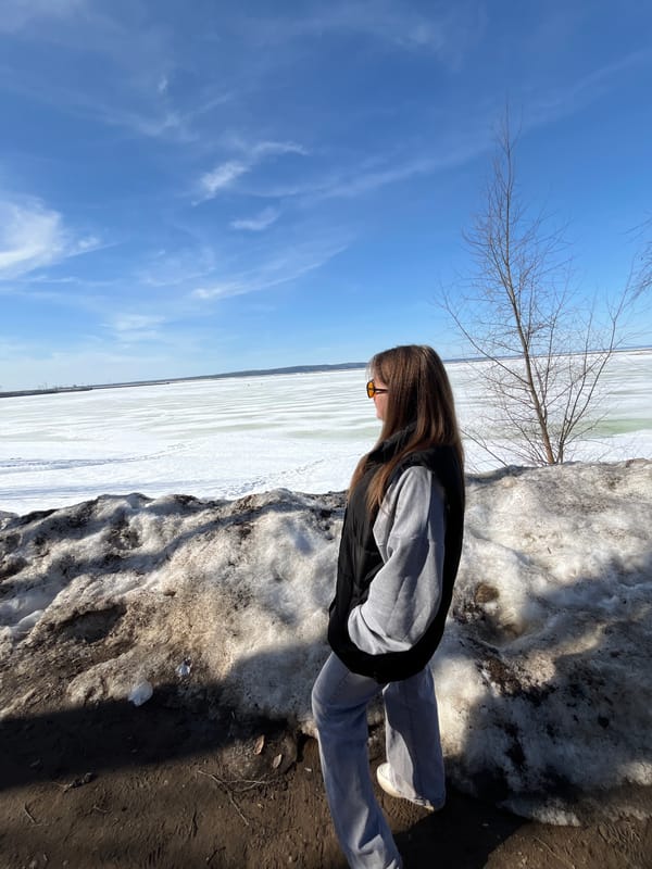 Woman explores snowy Chaikovsky park and reservoir during spring thaw