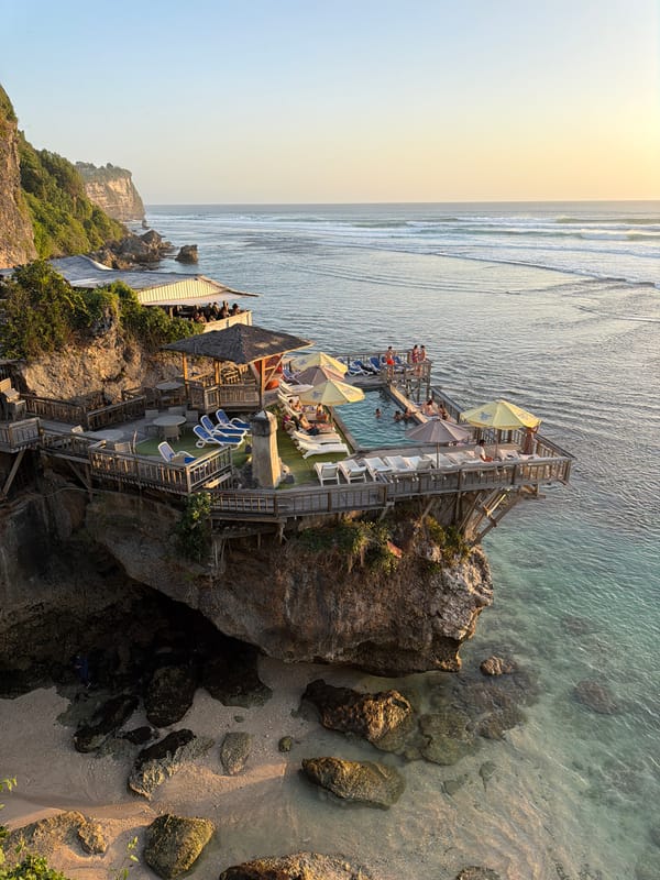 Sunset session at a Bali clifftop bar with surfers below