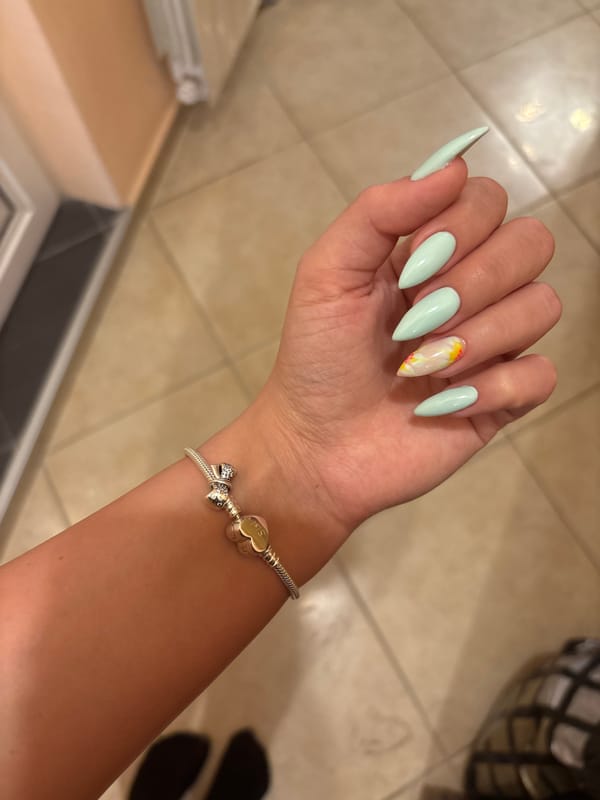 Stiletto nails in pale mint green, tiled floor backdrop
