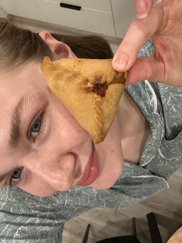 Person enjoys homemade triangular pastries in Kazan kitchen