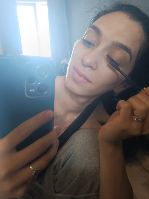 Woman applies makeup using smartphone mirror in Simferopol morning routine
