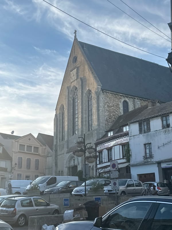 Stone church with clock face anchors a Gallardon street scene