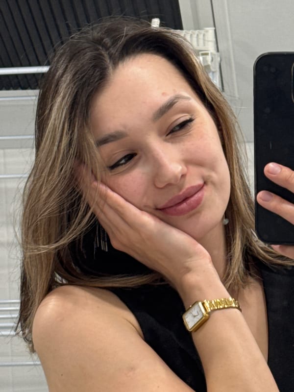 Woman takes bathroom selfies wearing black top and gold jewelry
