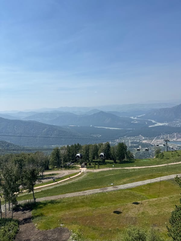 Gondola lift crosses green mountain terrain above Ozernoe, Russia