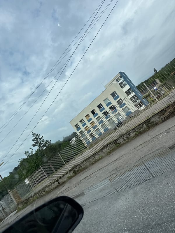 Modern white building with blue accents documented under overcast sky