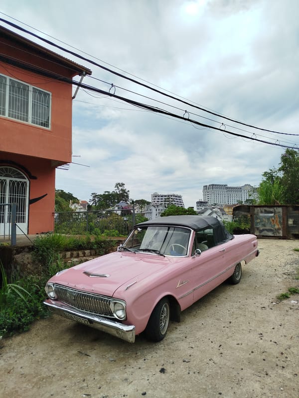 Vintage cars and scooter gather near colorful buildings in Da Lat
