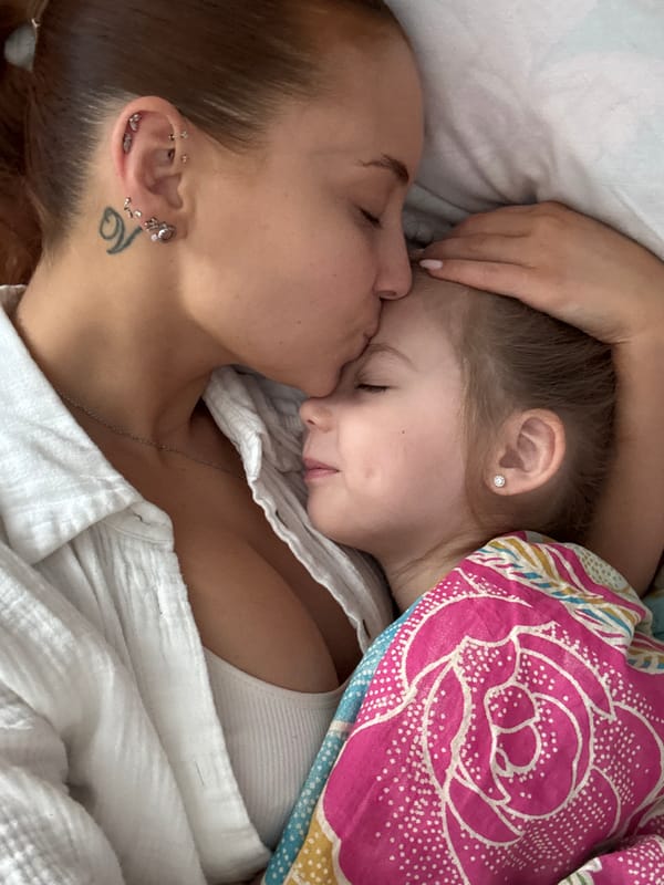 Mother and daughter share tender morning moment in bed