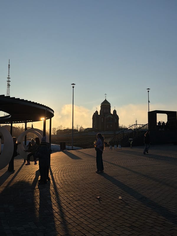 Pedestrians gather in brick plaza near church under cloudy skies