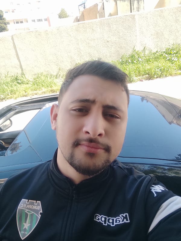 Man in team jacket stands by car in Meknes