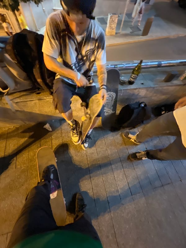 Small group hanging out on a Madrid sidewalk, summer evening