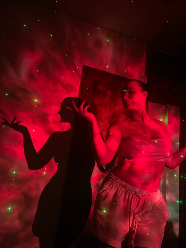 Person illuminated by red light, green lasers in dark room