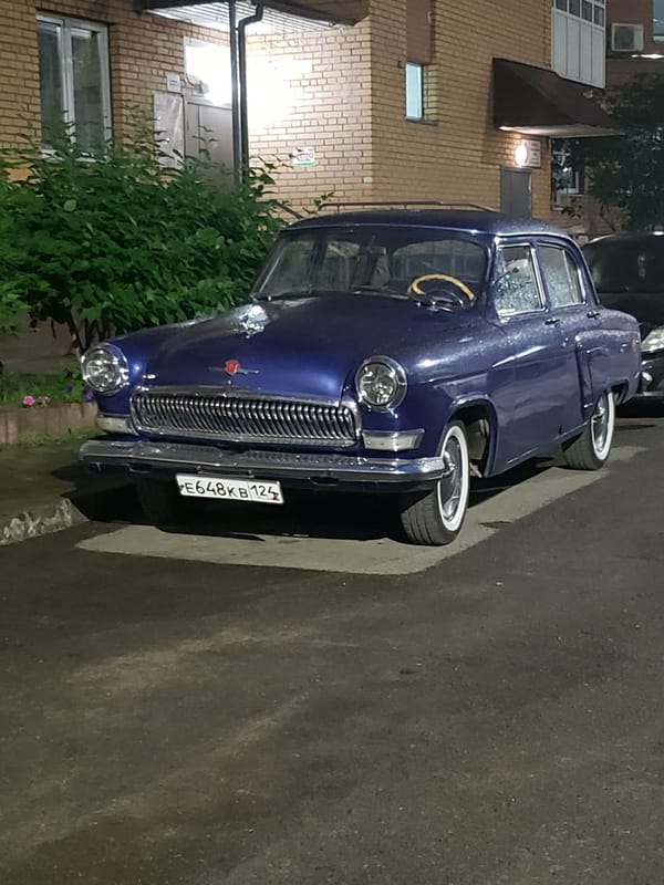 Classic GAZ-21 Volga parked on a wet street at night