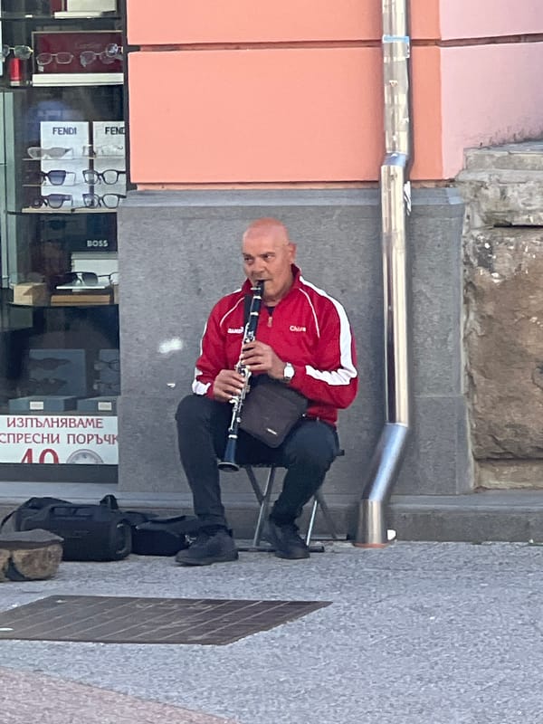 Street musician performs clarinet in urban commercial district