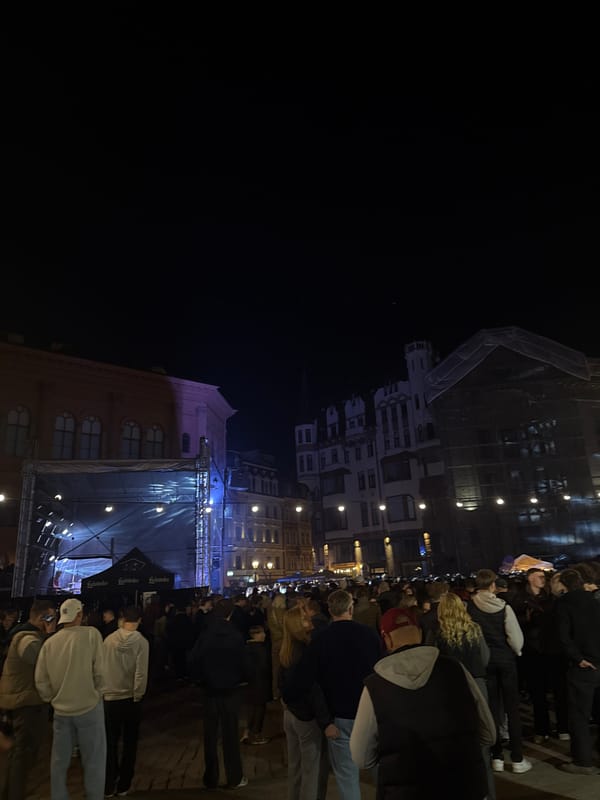 Evening crowd gathers around illuminated stage in Riga square