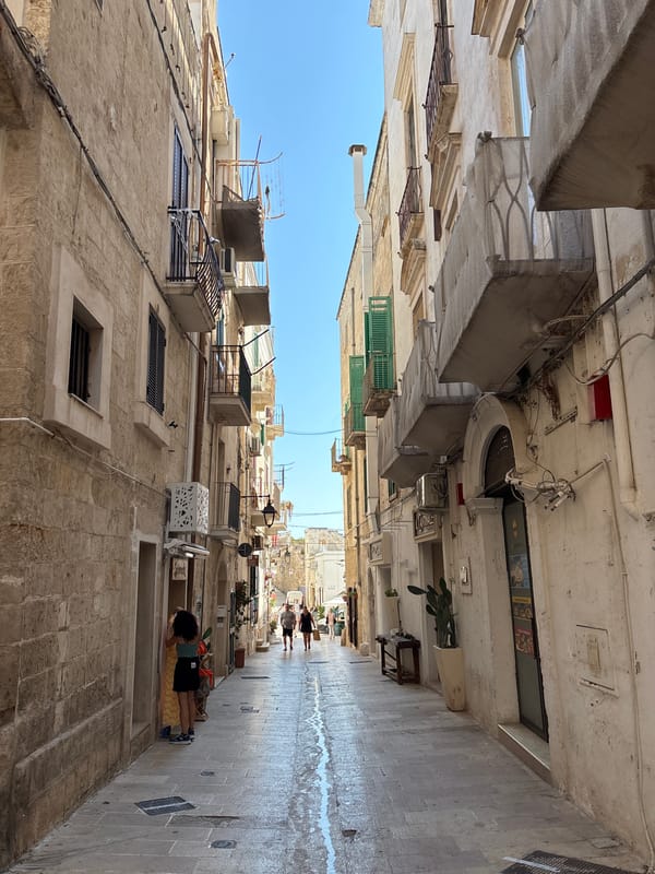 Narrow old-town street with stone buildings and a bell tower